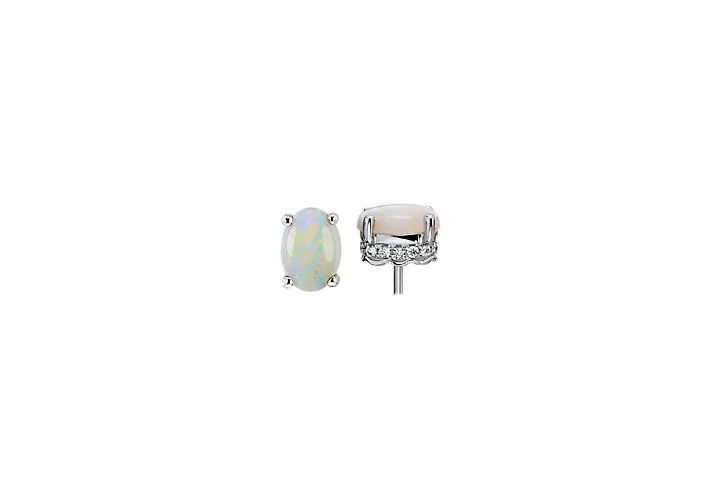 A pair of October birthstone stud earrings of smooth opal stones accented with lateral diamond detail in white gold